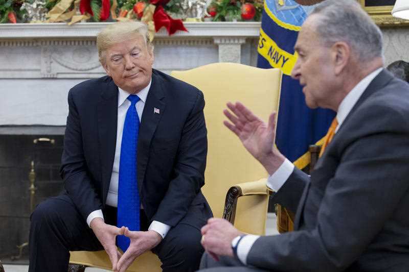 Trump listens on as US Senate Minority Leader Chuck Schumer speaks.