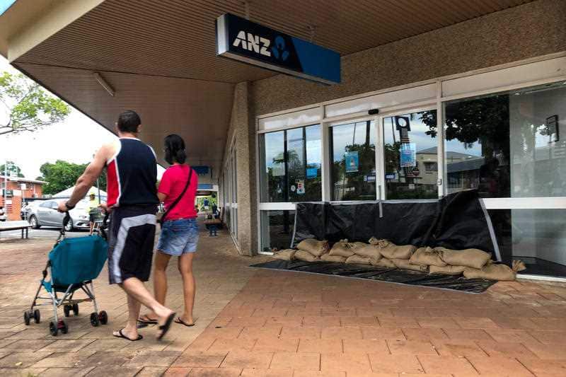 Pedestrians walk past the sandbagged entrance of ANZ Bank in Innisfail, Queensland.