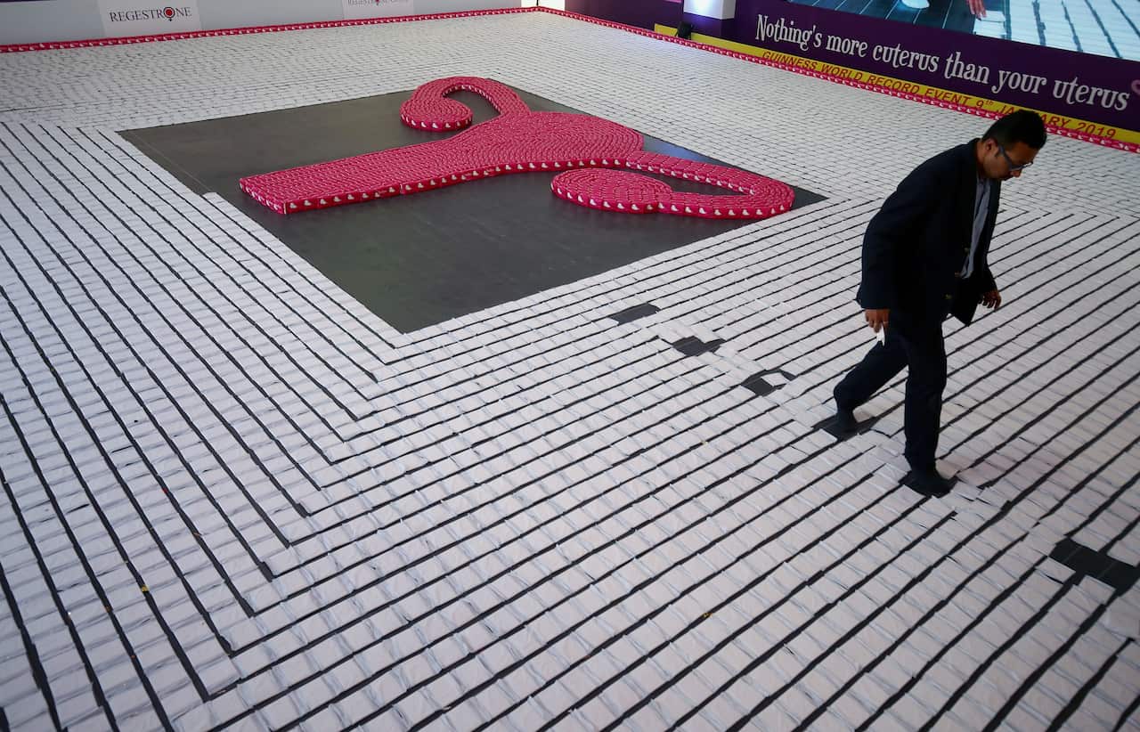 An Indian man walk between the sanitary napkins arranged during a successful attempt for a Guinness world record by creating the 'longest line of sanitary pads'