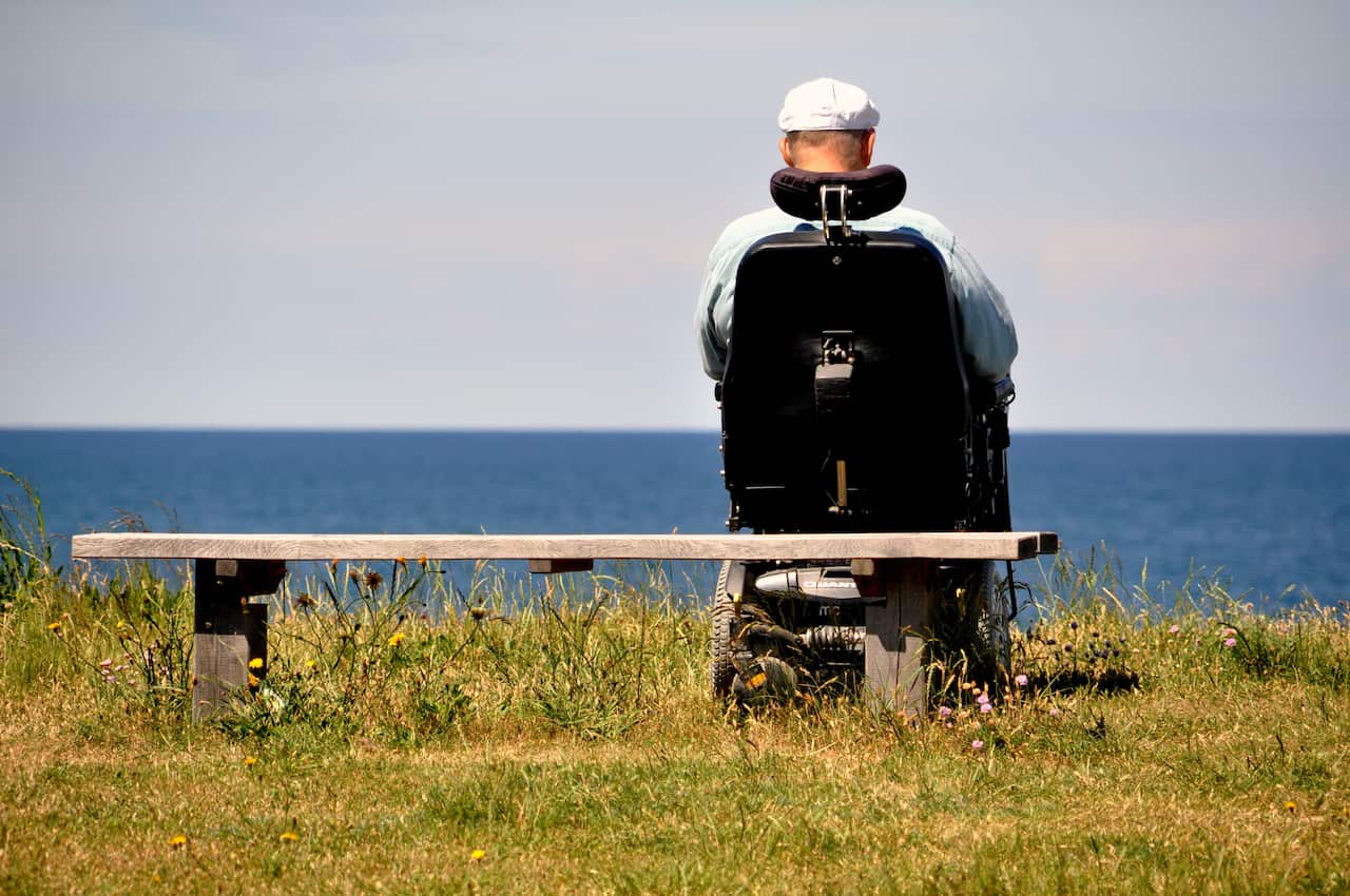 Man in wheelchair overlooks the sea.