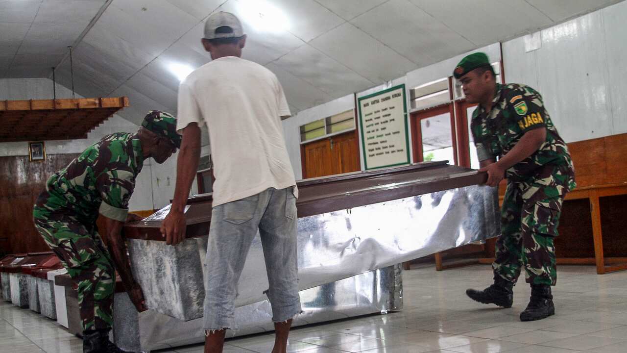 Indonesian military personnels and workers prepare coffins for construction workers, who were shot dead by suspected separatists, at a hall in Wamena, Papua.