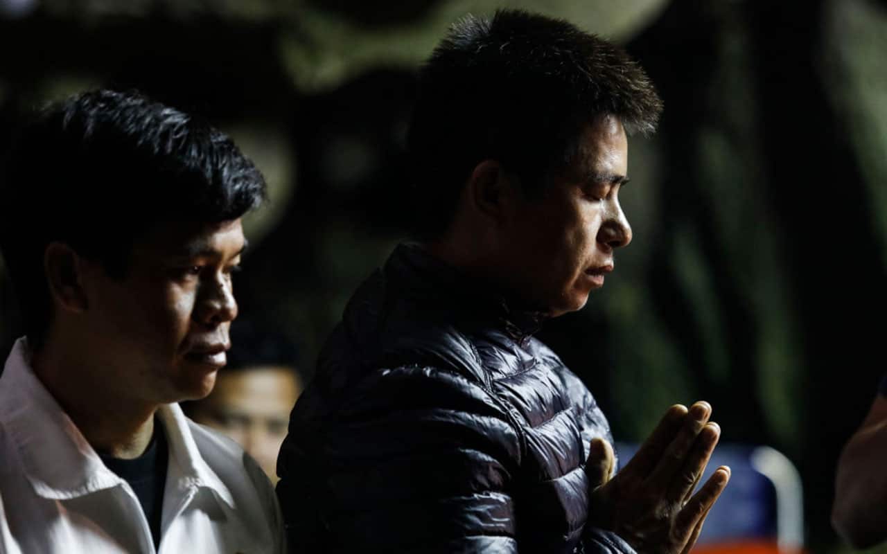 Family members and relatives pray at the entrance of Tham Luang cave.