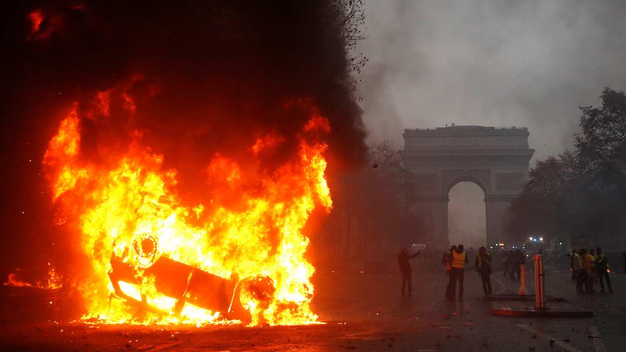 Cars burn, as protesters wearing yellow vests (gilets jaunes) clash with riot police near the Arc de Triomphe.