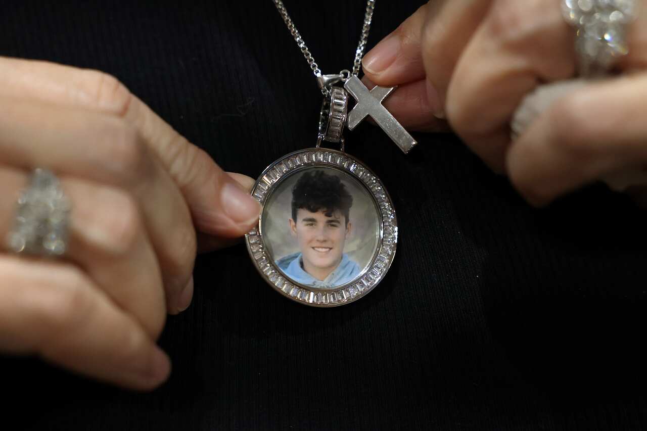 Gena Hoyer shows the pendant given to her by co-workers, bearing an image of her son, Luke Hoyer, 15, who was killed in the 2018 high school shooting.