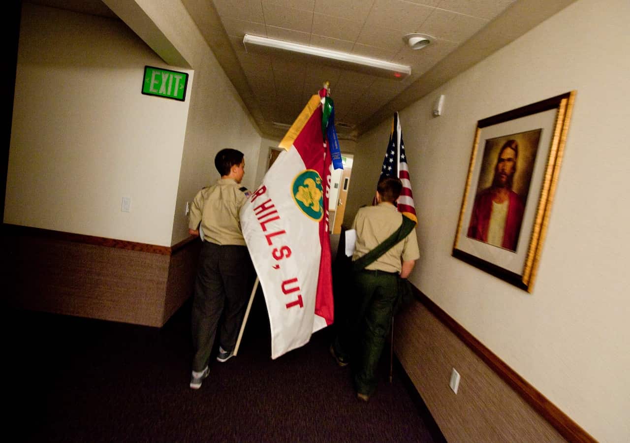 Boy Scouts carry the troop and American flag to a storage closet through the halls of a meeting house of the Church of Jesus Christ of Latter-day Saints. 