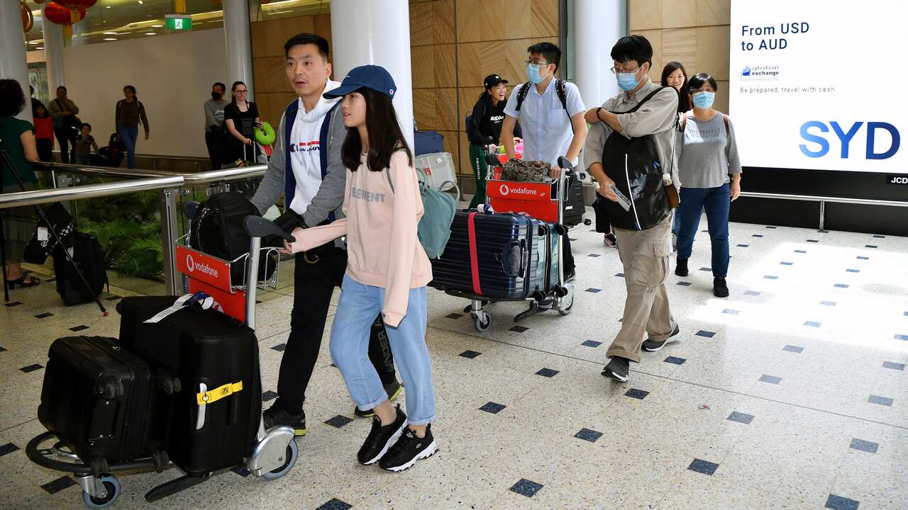 Passengers wearing protective masks arrive at Sydney International Airport in Sydney, 23 January 2020.  