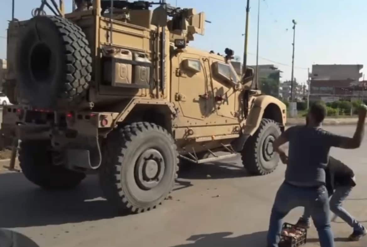 Kurdish locals pelt potatoes at a United States military vehicle pulling out of Syria.