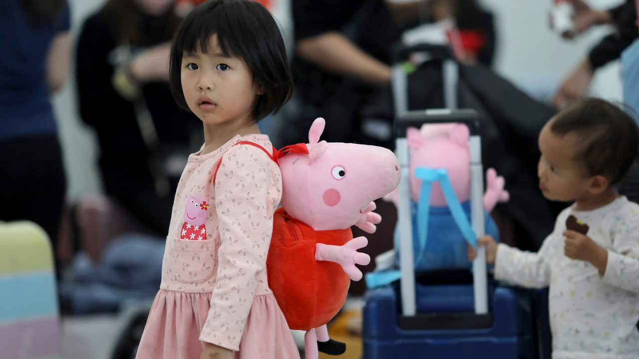 A Chinese girl carries a Peppa Pig-shaped bag with herself on her way back home during the Spring Festival travel rush at the Shenzhen North railway station.