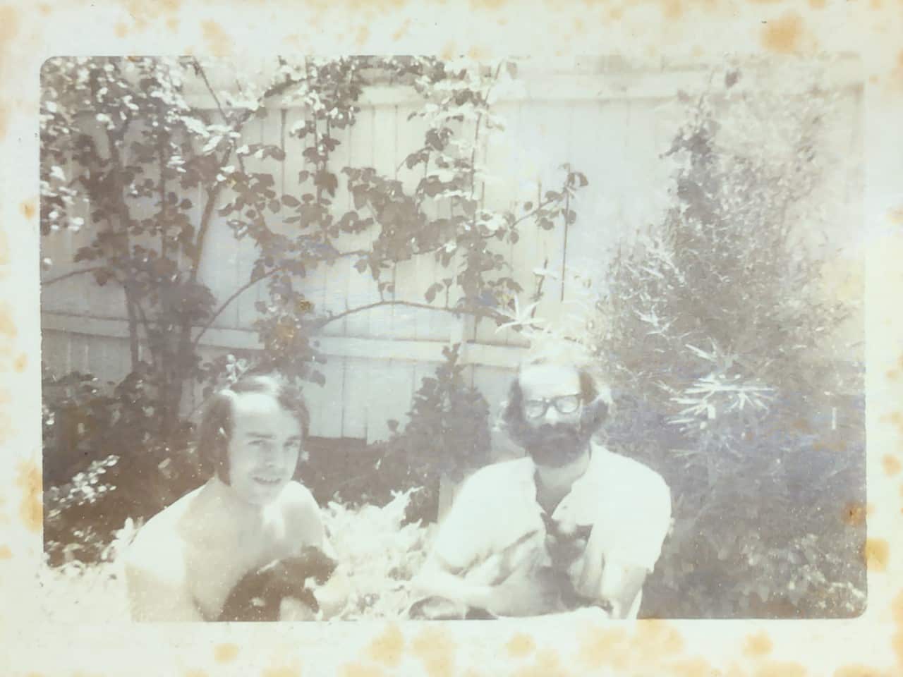 Peter and Bon at home in their backyard with their two cats. 