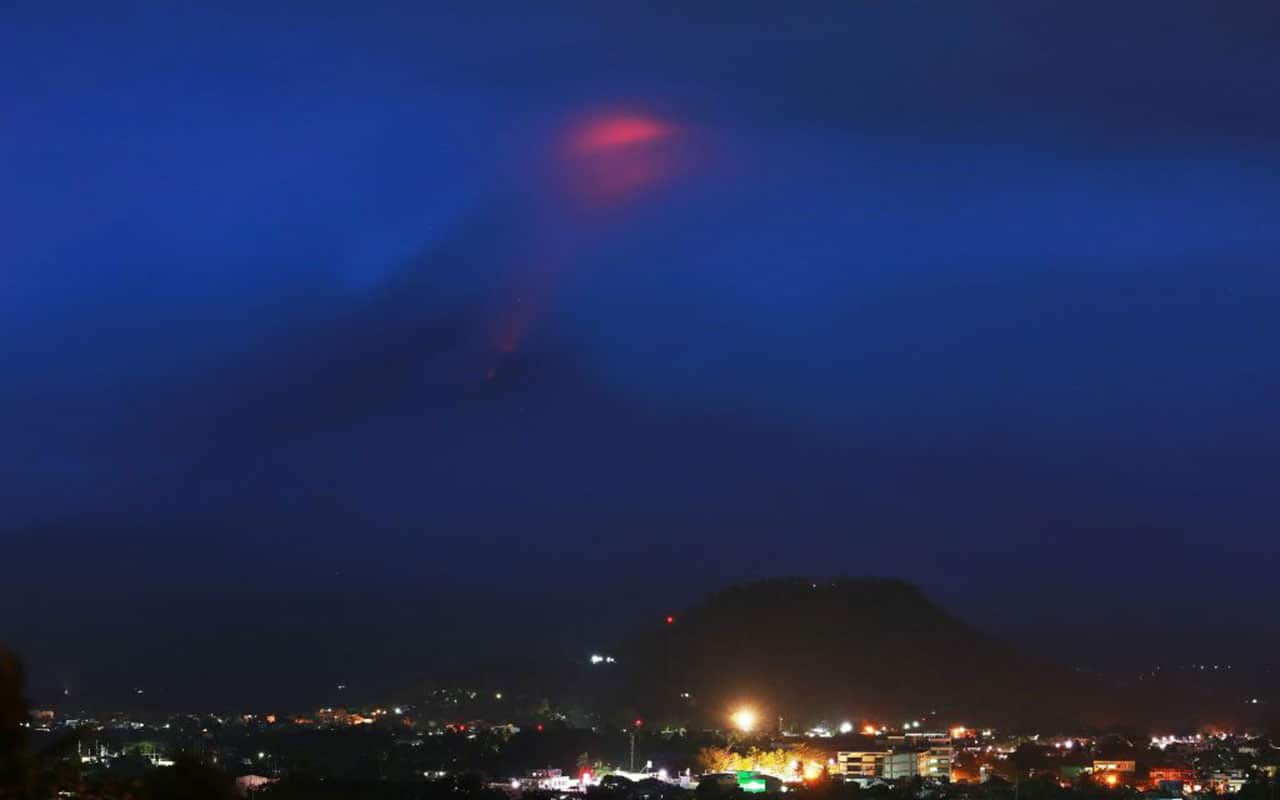 The glow of lava from the cloud-covered Mayon volcano as it erupts is pictured from the Philippine city of Legazpi in Albay province, early on January 15.
