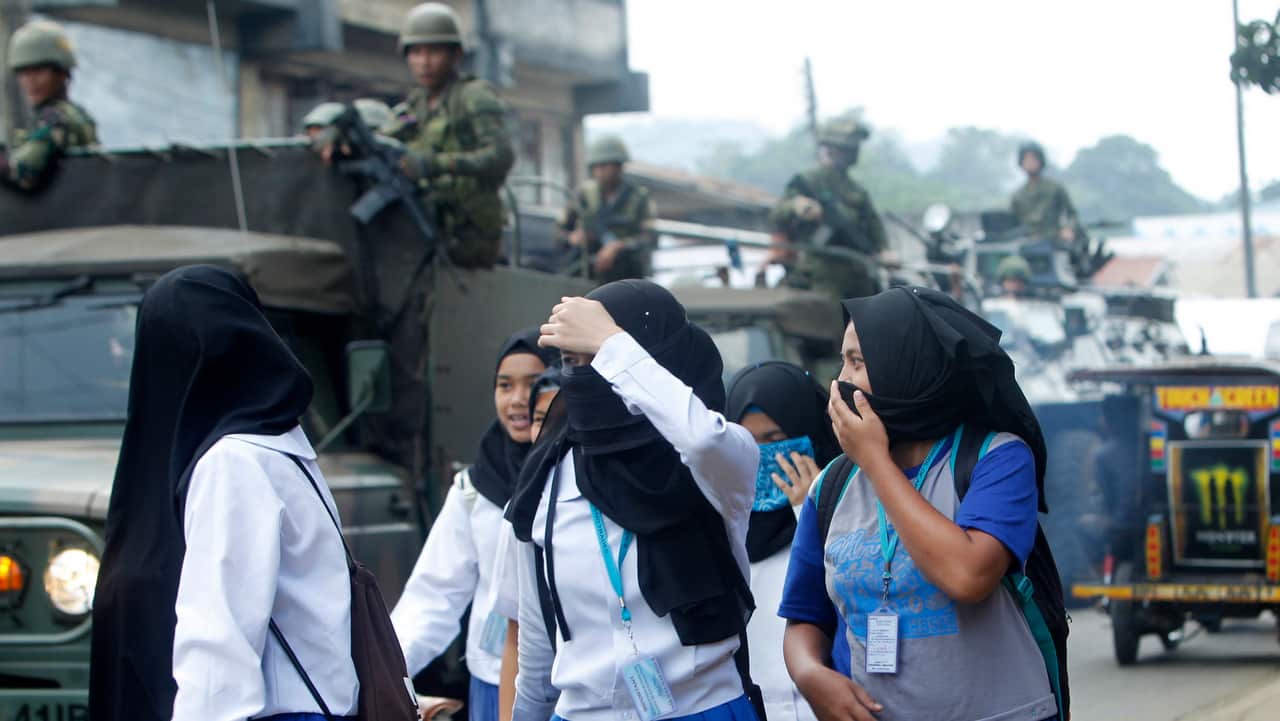 People react as Philippine government troops on armored vehicles conduct a patrol a day after the plebiscite on the Bangsamoro Organic Law (BOL) in Jolo town.