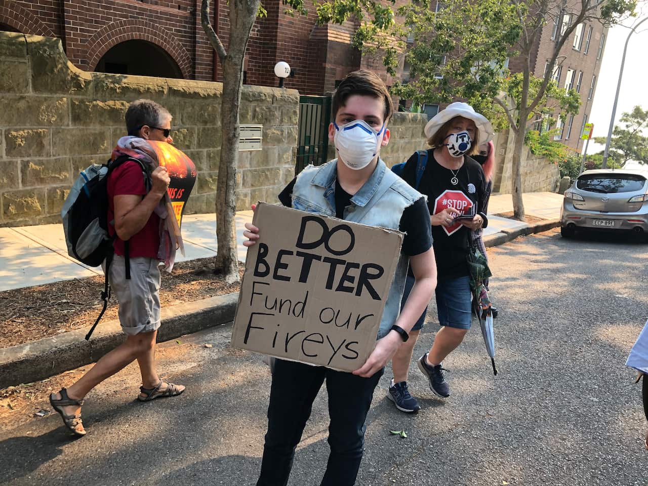 Kimberley holds a sign reading "do better, fund our fireys"