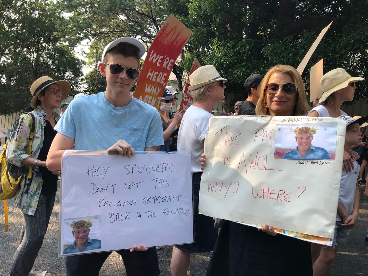 Callum holds a sign with a message for Peter Dutton