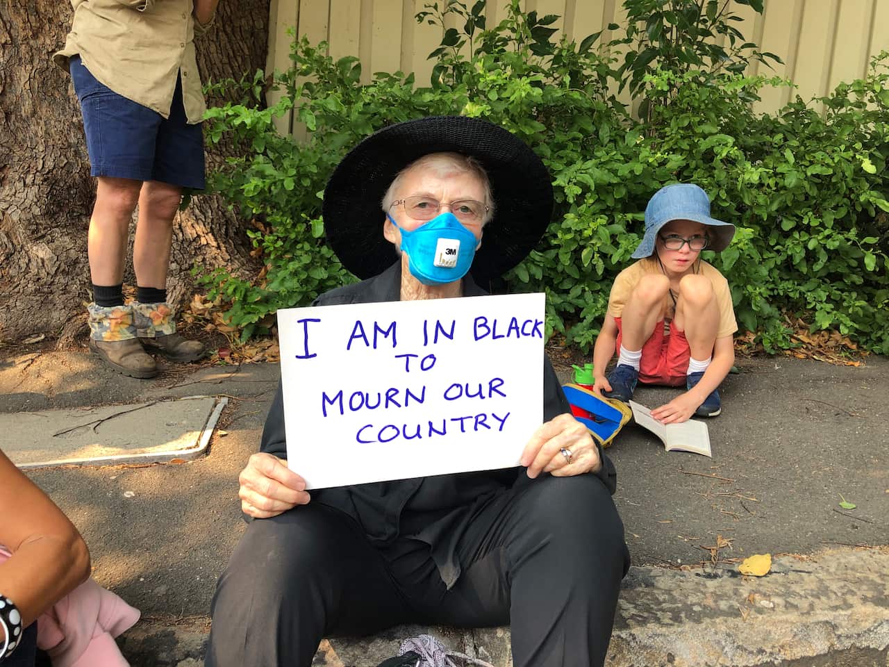 Petrina came to the protest dressed in black, holding a sign reading "I am in black to mourn our country".
