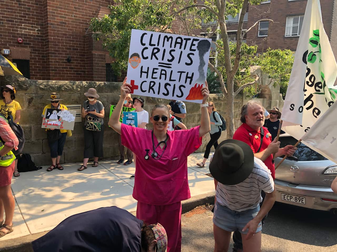 Lucy holds a sign reading "climate crisis = health crisis"