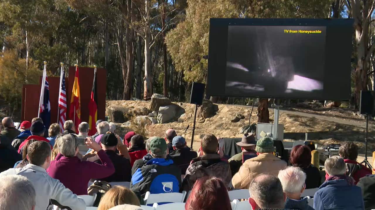 The crowd watches a replay of the moon landing