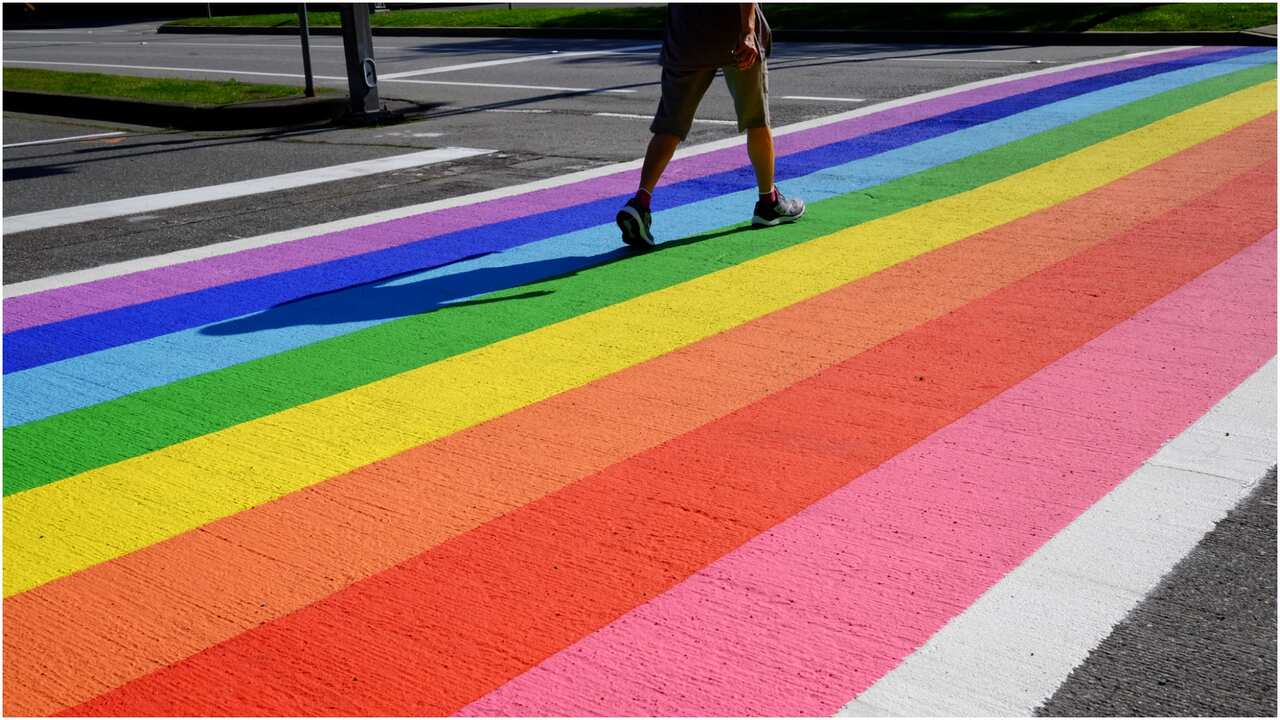 A person walking on a road with an lgbtiq+ rainbow pattern