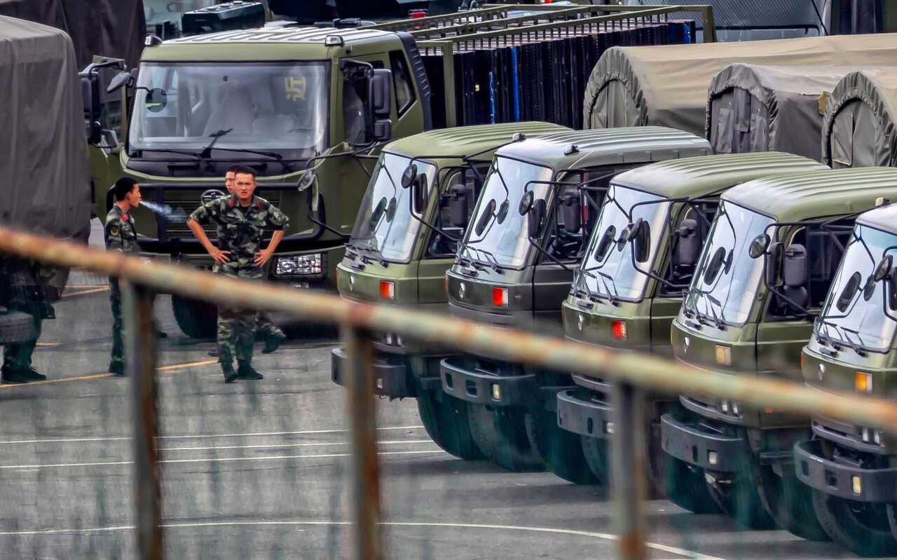 A members of People's Armed Police Force walk by vehicles at the Shenzhen Bay Sports Centre.  China has deployed paramilitary personnel, just across the border.