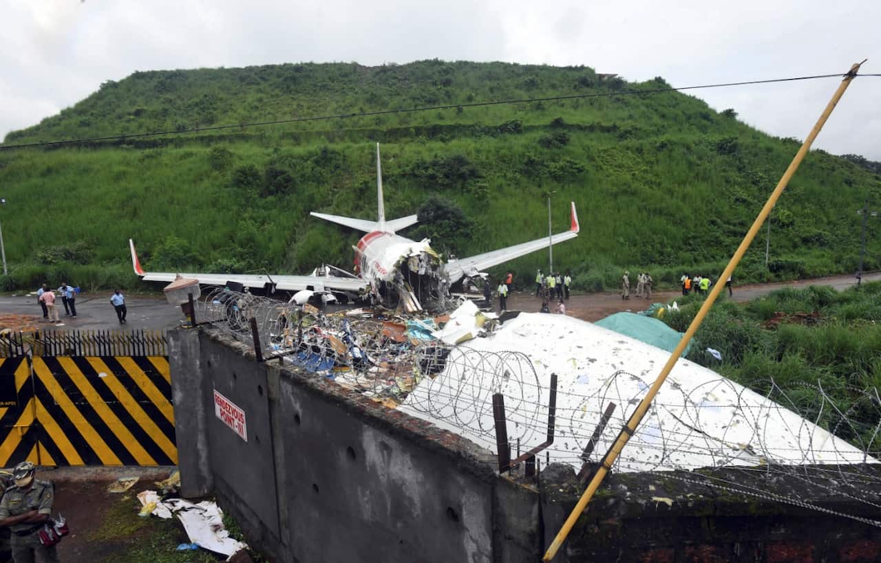 Officials stand by the debris of the Air India Express flight that skidded off a runway while landing in Kozhikode, Kerala state, India, Saturday, Aug. 8, 2020.