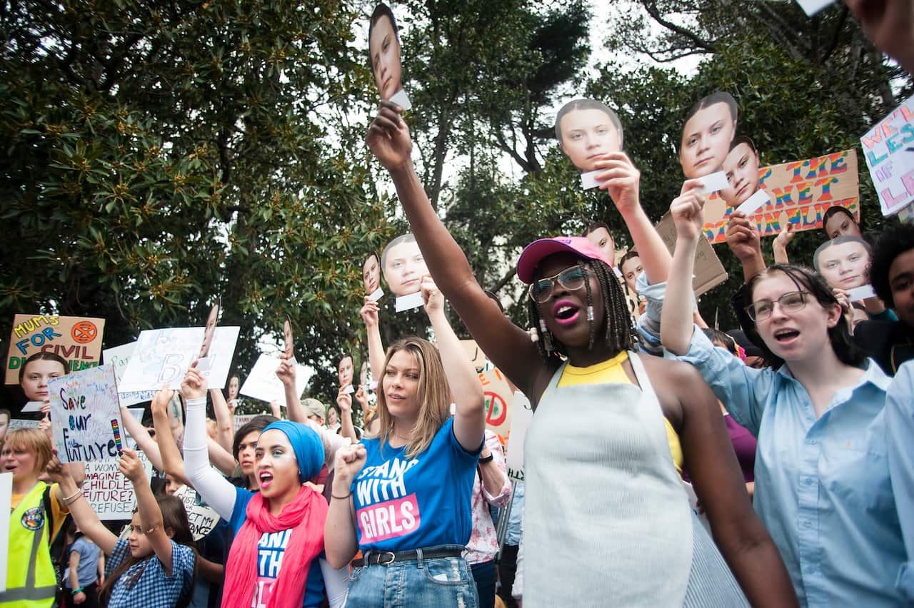 Girls and young women hold up Greta Thunberg faces at the Climate Strike. 
