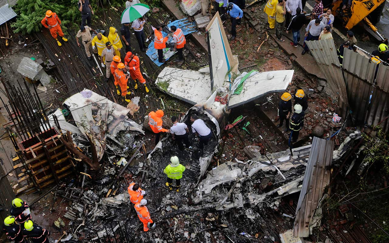 Rescuers stand amid the wreckage of a private chartered plane that crashed in Ghatkopar area, Mumbai, India, Thursday, June 28, 2018. 