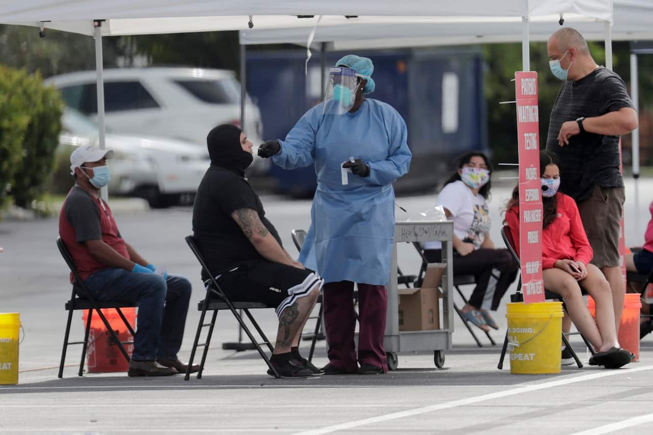 A Florida health care worker administers COVID-19 tests