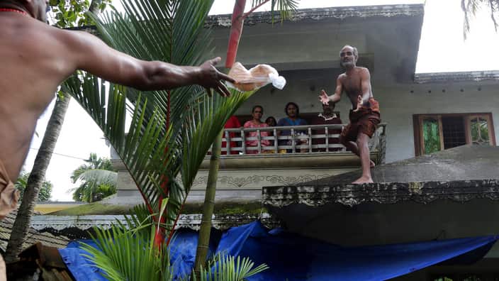 A volunteer throws a pack of bread towards a family stranded in a flooded area in Chengannur in the southern state of Kerala, India.
