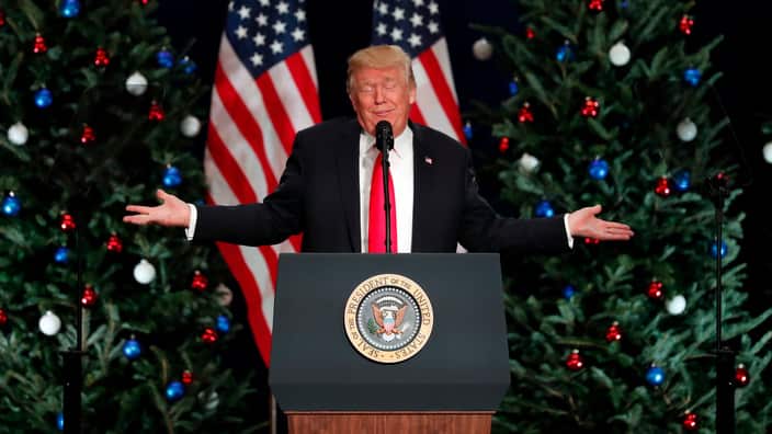 Then US President Donald Trump standing behind a lectern and gesturing with his hands