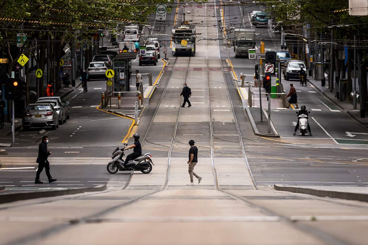 People are seen crossing Collins Street in Melbourne, the world's most locked-down city