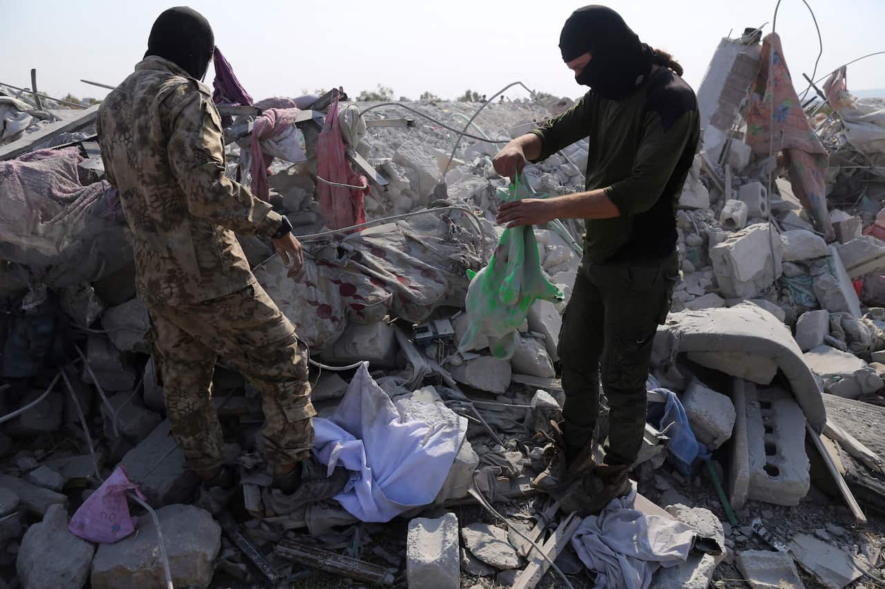 People look at a destroyed house in Idlib province after the US operation targeting Abu Bakr al-Baghdadi