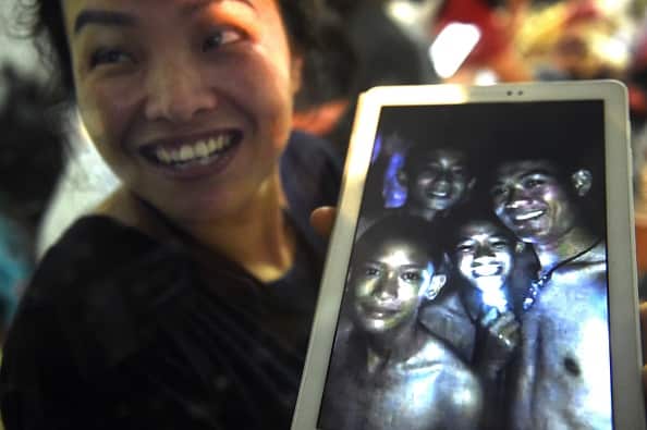A family member shows a picture of four of the twelve missing boys near the Tham Luang cave at the Khun Nam Nang Non Forest Park in Mae Sai on July 2, 2018.