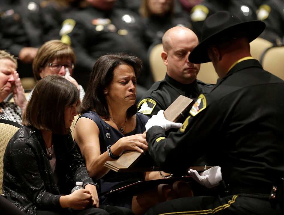 2014:The wife of officer Danny Oliver is presented with a flag during a memorial service. Oliver and Michael Davis Jr. were shot and killed in a shooting spree.