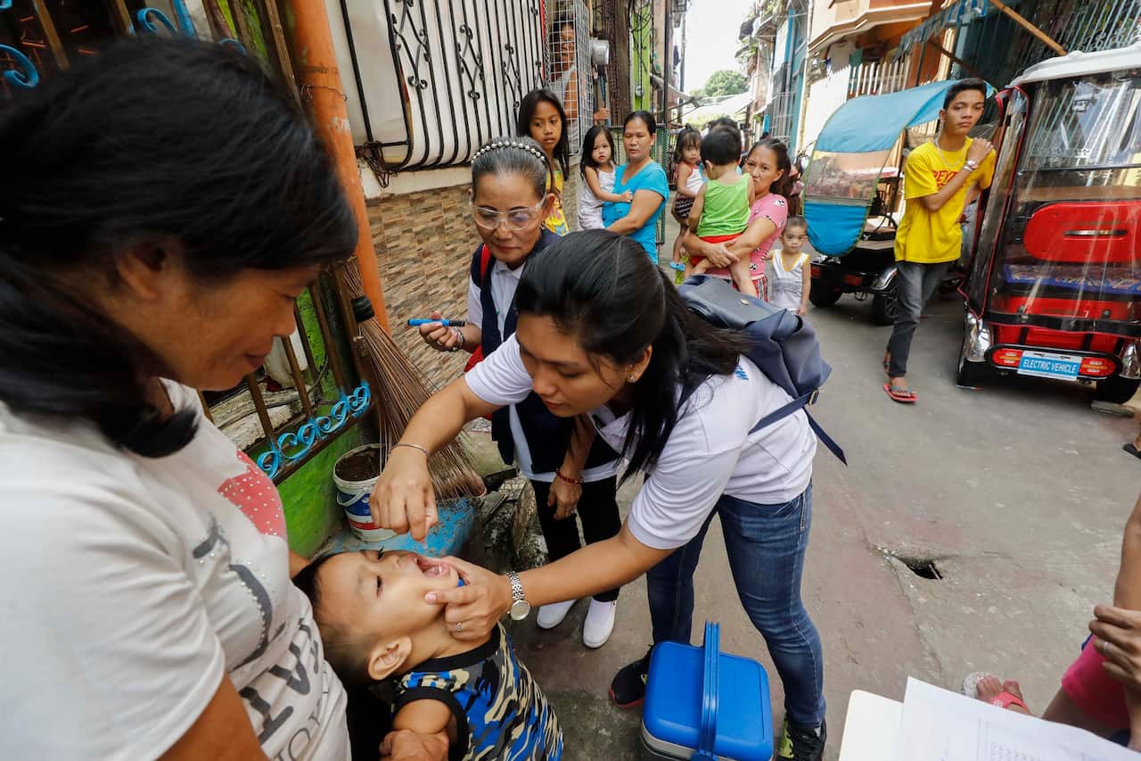 A child receives a dose of polio vaccine from a Filipino health worker in Marikina, Philippines on 14 October 2019. 