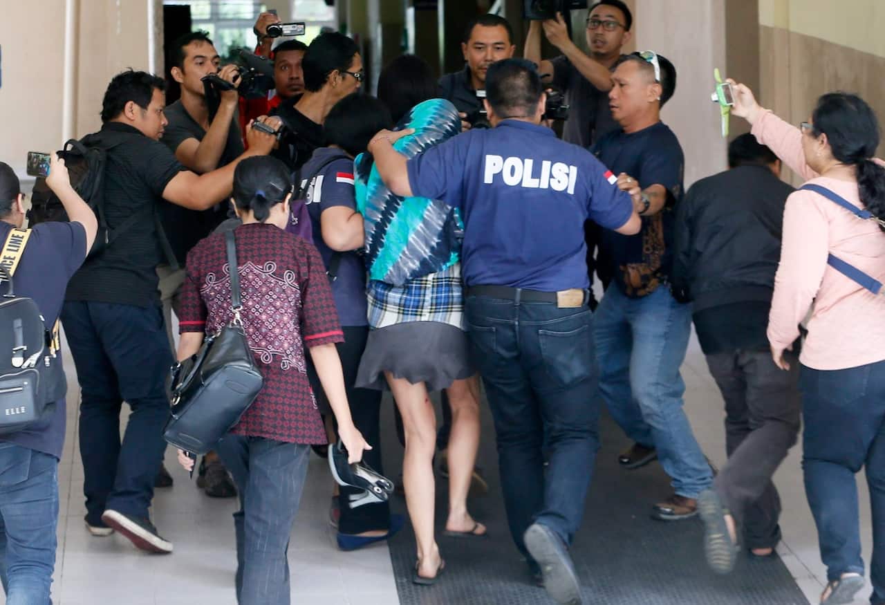 Australian Sara Connor (C, with hood) is escorted by police officers