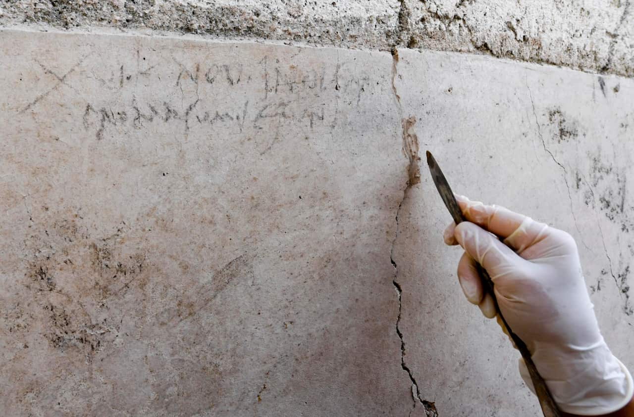 An archaeologist checks inscriptions on a wall during new excavations at the Pompeii archaeological site