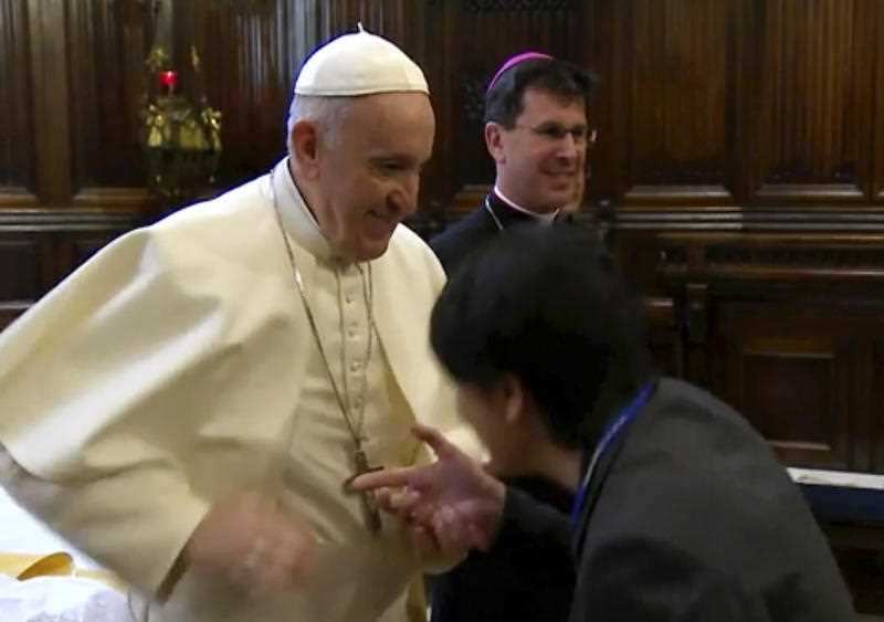 Pope Francis moves his hand as a pilgrim tries to kiss his ring, in Loreto, Italy.