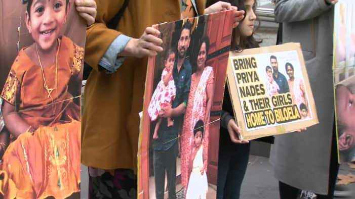 Protesters hold photos of the family facing imminent deportation.