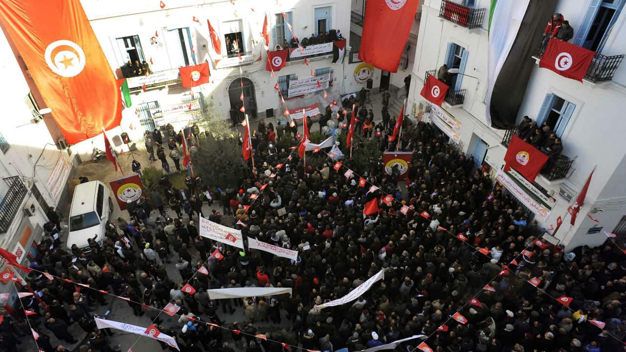 Tunisian people march with national flags.