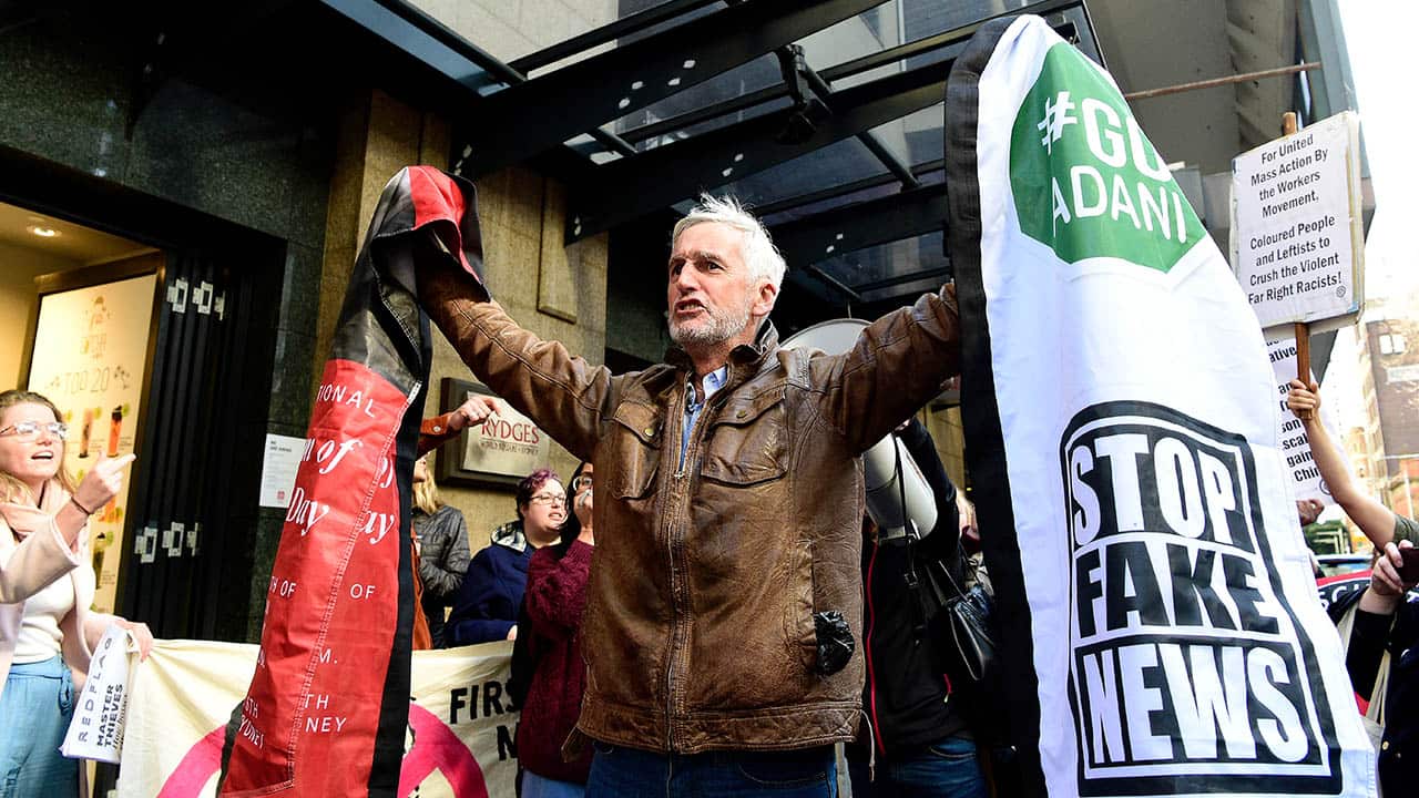 A Conservative Political Action Conference attendee brandishes a sign as protesters from Unite Against The Far Right and NUS Against Racism jeer.