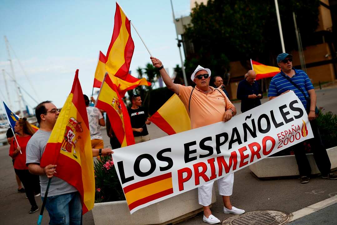 People holding 'Spaniards first' banners protest the arrival of the Aquarius rescue ship in Valencia.