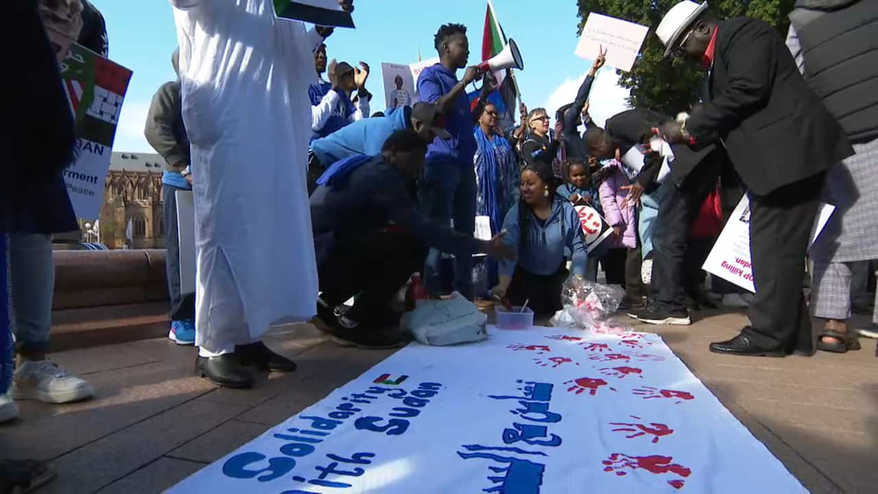 Sydney protesters ink their hands in red and stamp it on a banner to show solidarity with the Sudanese people.