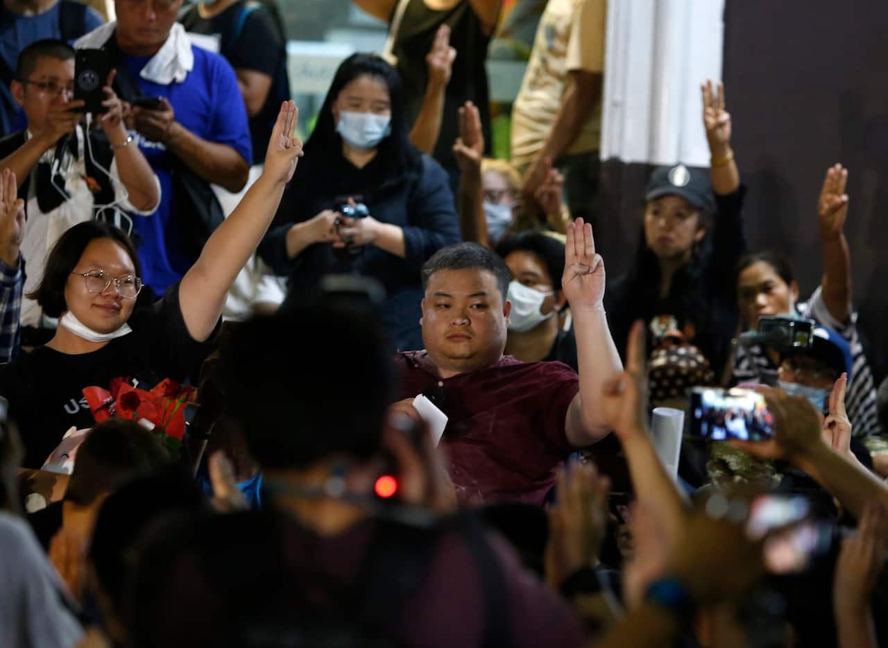 Parit Penguin Chiwarak, and Panusaya Rung Sithijirawattanakul raising up their three-finger salute with their supporters. 