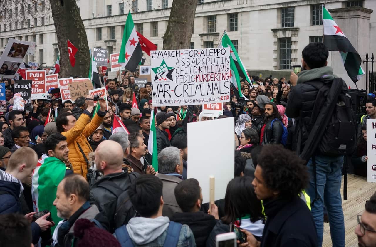 Signs are held up as hundreds of Syrians and people standing in solidarity with them march for Aleppo on December 17, 2016 in London. (AAP)