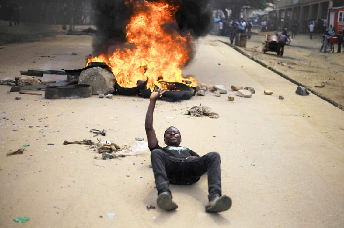 Protesters act in front of the camera after setting off a burning barricade in the Eastern Congolese town of Beni Thursday Dec. 27, 2018 (AAP)