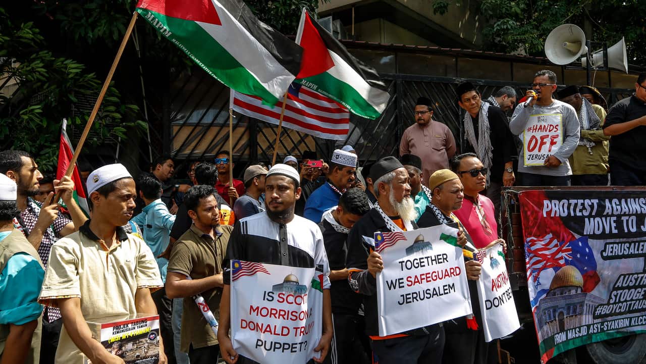 Pro-Palestinian demonstrators wave flags of Palestine and display protest banners outside the Australian Embassy in Kuala Lumpur, Malaysia.
