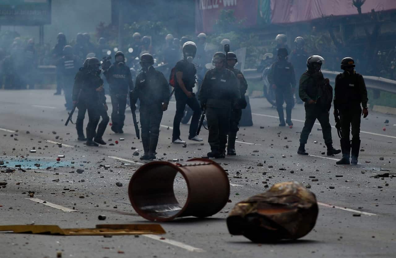 Bolivarian National Guard officers clear a barricade set by protesters during an opposition May Day march in Caracas, Venezuela, Monday, May 1, 2017. (AAP)