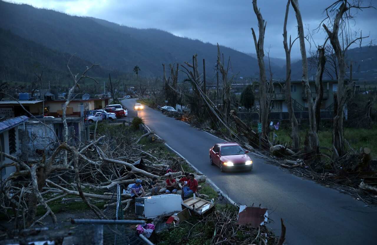  In this Sept. 26, 2017, file photo, neighbors sit on a couch outside their destroyed homes as sun sets in the aftermath of Hurricane Maria