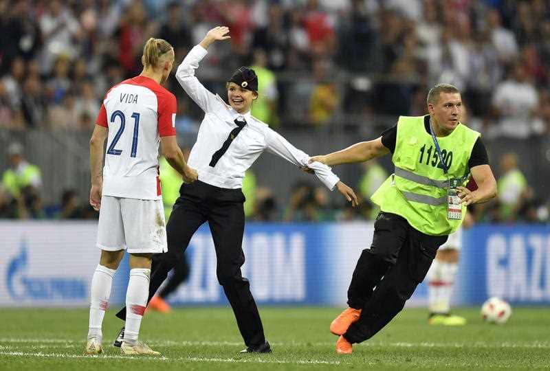 Stewards pull a member of Pussy Riot off the pitch after she stormed onto the field and interrupted the final match between France and Croatia.