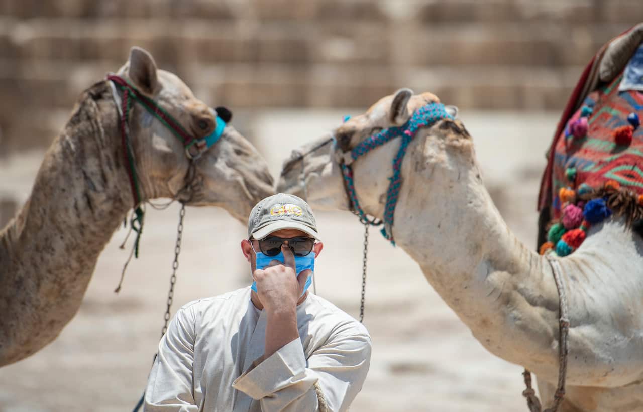 A man wears a protective face mask outside the Great Pyramids of Giza.