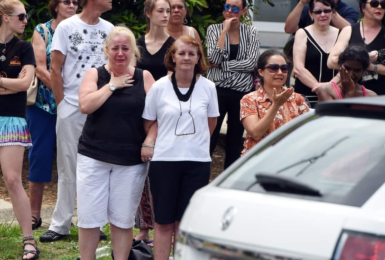 Local residents react as a hearse carrying one of the coffins of eight children drives by Murray street in the suburb of Manoora (AAP)